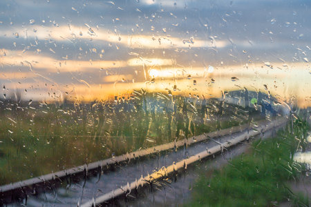 Raindrops on the window of a train at sunset in the summerの写真素材