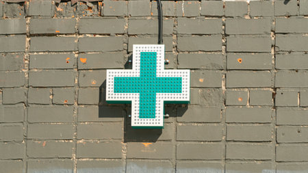 Green medical cross on the wall of the building. medical background.の写真素材
