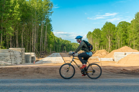Unidentified cyclist riding a bicycle on the road.の写真素材