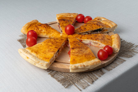 Pizza with ham, cheese and cherry tomatoes on a wooden boardの写真素材