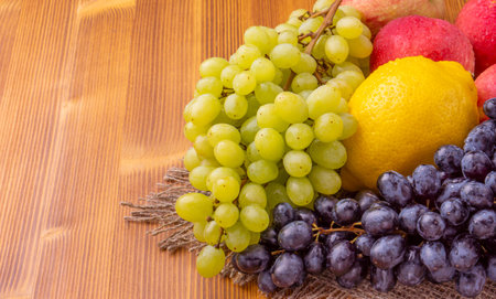 Bunch of grapes, lemon and apples on a wooden background.の写真素材