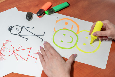 Women's manicured hands draw with felt-tip pens on a white sheet. At the desk. top viewの写真素材