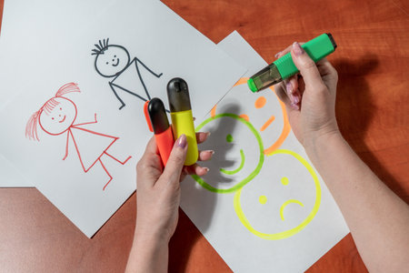 Women's manicured hands draw with felt-tip pens on a white sheet. At the desk. top viewの写真素材