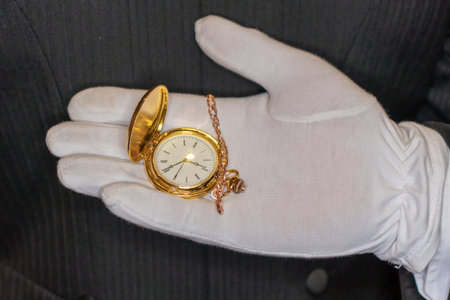 Hand in white glove holding antique pocket watch, closeup of photoの写真素材