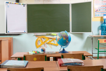 Classroom with a globe in the foreground and a blackboard in the backgroundの写真素材