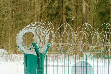 Barbed wire on the fence, a fence made of steel grating. Spiral barbed wire with sharp steel spikes...