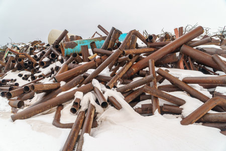 Pile of old rusty metal pipes in the snow, industrial backgroundの写真素材