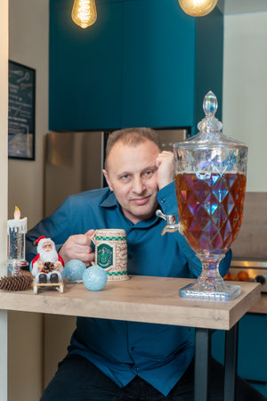A man in a blue shirt sits at a table with a cup of tea and a candlestick.の写真素材