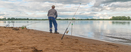 Fisherman with a fishing rod on the shore of the lakeの写真素材
