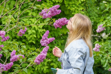 blonde girl with a bouquet of lilacs in the gardenの写真素材