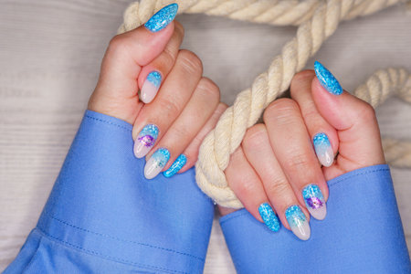 Manicure in the marine style. Photos with beautiful well-groomed female nails. selective focus.の写真素材