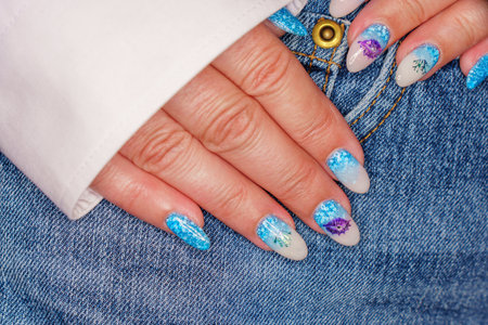Female hand with blue nail design. Glitter nail polish manicure.の写真素材