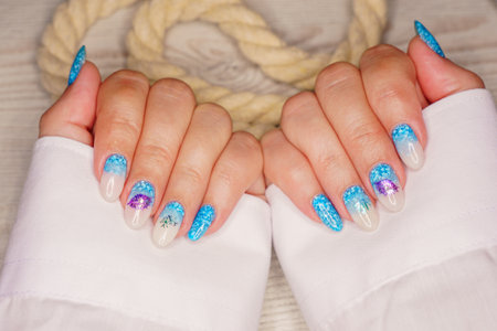 Manicure in the marine style. Photos with beautiful well-groomed female nails. selective focus.の写真素材