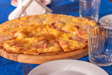Pizza with ham, cheese and pineapple on a blue tableclothの写真素材