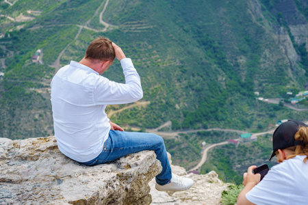 Man sitting on the edge of a cliff and looking at the landscape