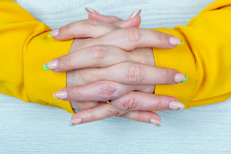 Female hands with manicure and nail design. Woman in yellow clothes.の写真素材
