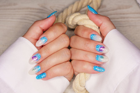 Female hands with blue nail design. Glitter blue nail polish manicure. Woman hands with French manicure.の写真素材