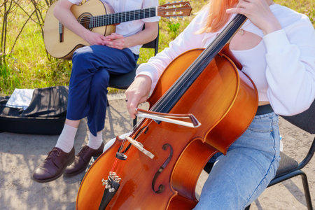 Couple of musicians playing the cello and guitar in the parkの写真素材