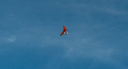 Red glider flying in the blue sky with white clouds on a sunny dayの写真素材