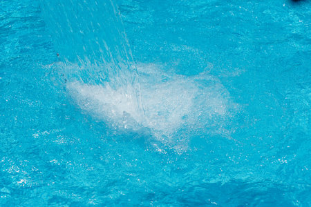 Water splash in swimming pool, close up. Blue water background.の写真素材