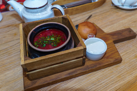 Red borscht with sour cream in a wooden box on the table