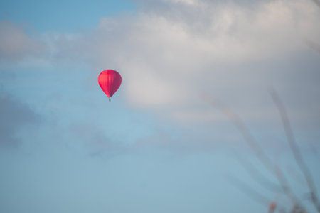 Red hot air balloon in the blue sky with white clouds, soft focusの写真素材