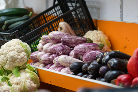 Fresh eggplants, striped aubergines and cauliflower displayed at local market. Organic vegetables and healthy food concept in grocery store.の写真素材