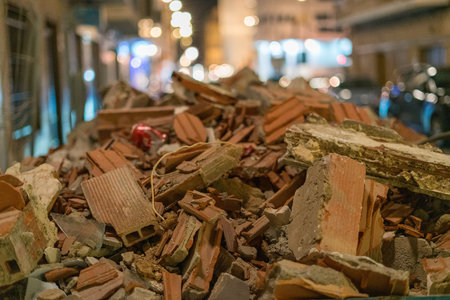 Close up photo of broken bricks and concrete rubble on urban street at night with blurred city lights background construction renovation concept.の写真素材