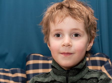 Boy smiles and looks at turn blue plaid background