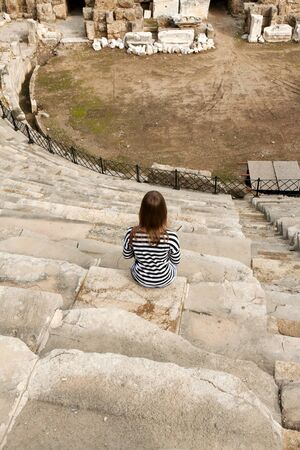 Girl with a striped dress sitting in the amphitheaterの写真素材