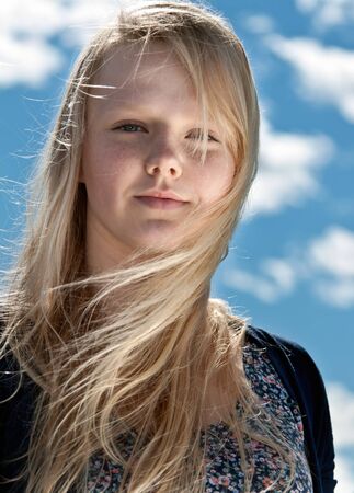 portrait of a beautiful blonde with freckles on the background of sky with cloudsの写真素材