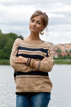 portrait of a girl in a beige striped sweater on the lakeの写真素材