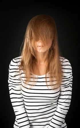 hair covers her face with a young girl on a black backgroundの写真素材