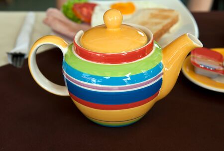 colored striped teapot on the table with breakfastの写真素材
