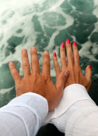 Men's and Women's tanned hands against the raging seaの写真素材
