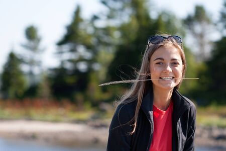 beautiful girl with an ear in his teeth against the backdrop of pine forests. The limited depth of field.の写真素材