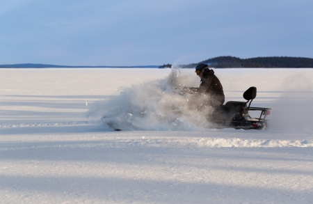 man rushes a snowmobile on a snow plainの写真素材