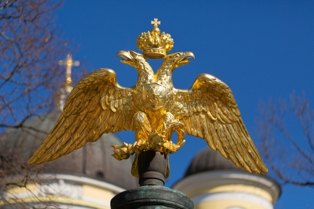 golden double-headed eagle on a background of blue sky and the domes of the churchの写真素材