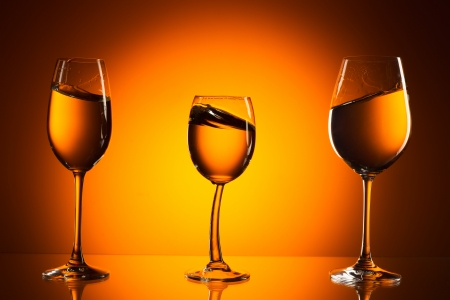 Three glasses on orange background with the liquid. On the background of orange light spot.の写真素材