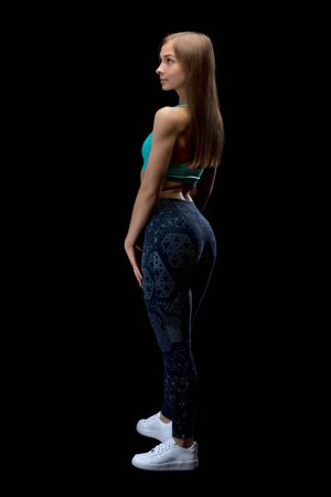 Brunette fitness woman in sportswear from the back in the studio. Isolate on black.の写真素材