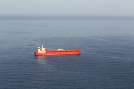 Red tanker ship at sea, the mist on the horizon.の写真素材