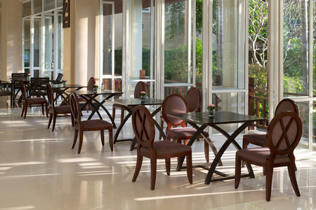 Empty restaurant, windows with tropical plants.