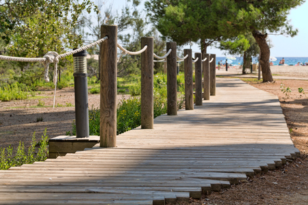 paved trail with wooden rope handrail leading to beautiful ocean beachの写真素材