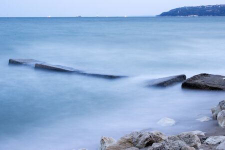 beach waves lighthouse on the horizon great clouds evening landscapeの写真素材