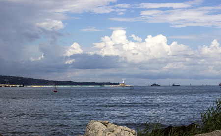 beach waves lighthouse on the horizon great clouds varnaの写真素材