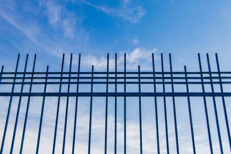 blue sky behind a fence of a fence restriction of freedomの写真素材