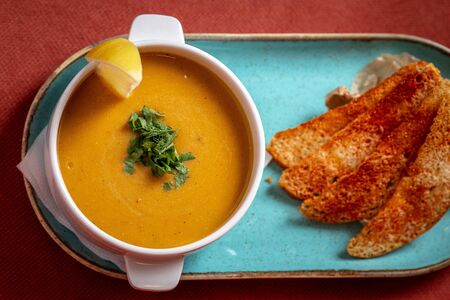 lentil soup with crackers and lemon on a red backgroundの写真素材