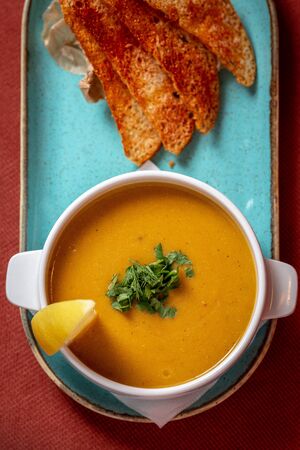 lentil soup with crackers and lemon on a red backgroundの写真素材