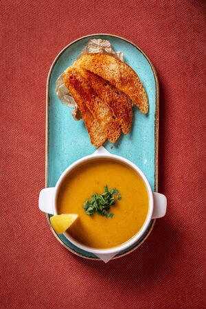 lentil soup with crackers and lemon on a red backgroundの写真素材