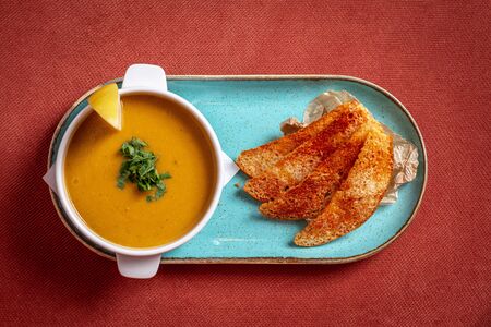 lentil soup with crackers and lemon on a red backgroundの写真素材